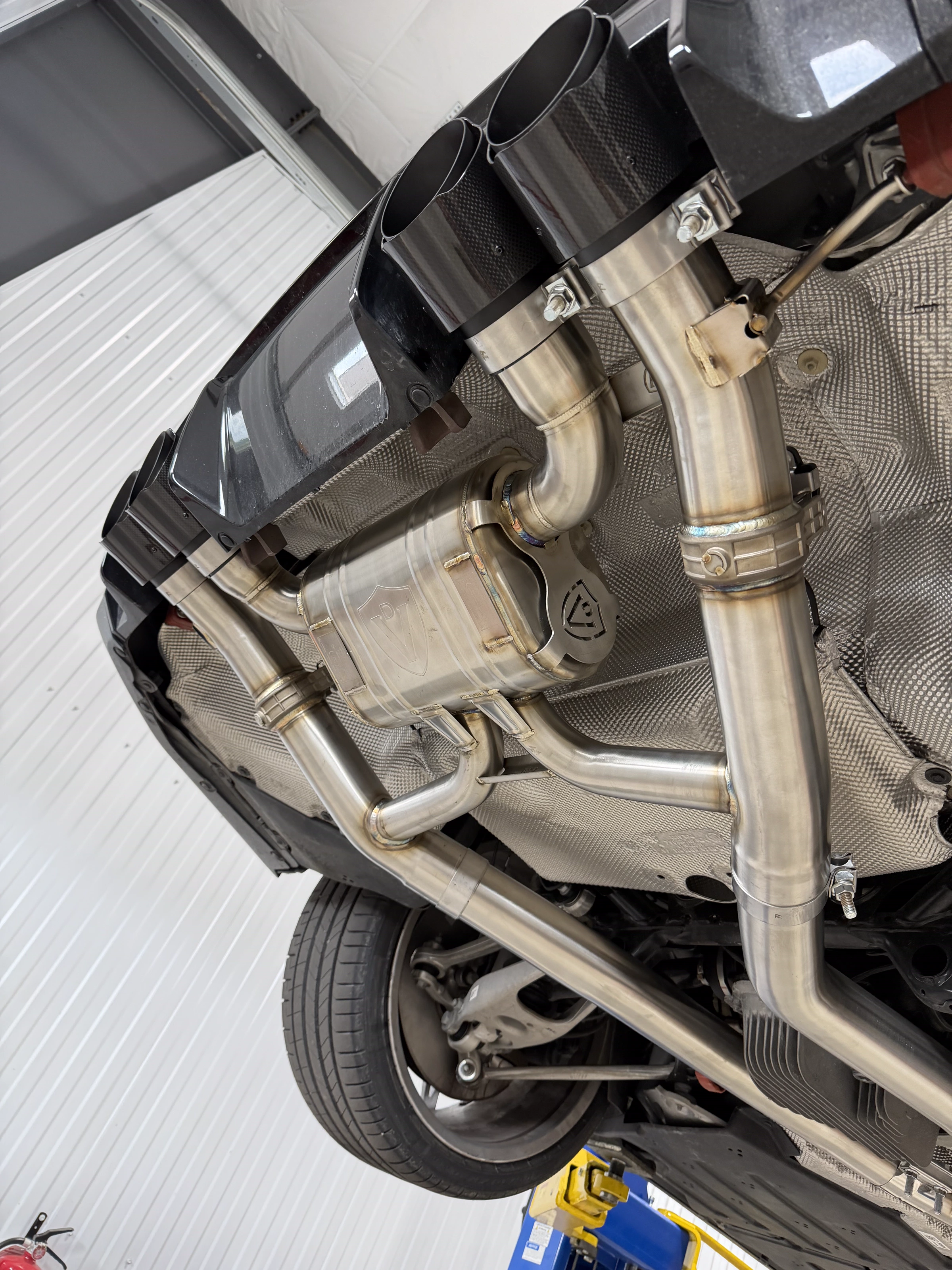 Custom stainless exhaust under a BMW on the lift at The Upgrade Shop
